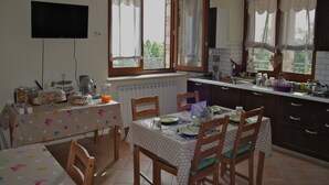 A kitchen with a dining table, chairs, and a TV mounted on the wall. - B&B Lavanda e Rosmarino (Assisi)