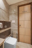 A bathroom with a marble wall, a wooden door, a white sink, and a shower.