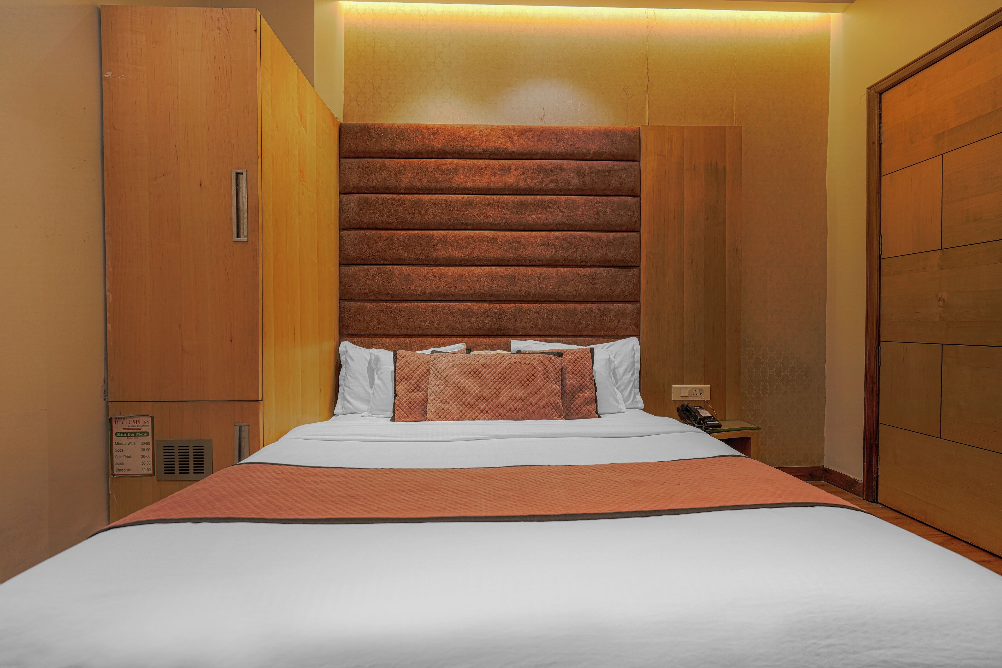 Habitación de hotel con una cama grande, cabecero de madera y una mesita de noche con teléfono.