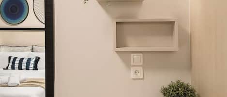 Una habitación moderna con una cama, un estante montado en la pared con plantas y una mesita.