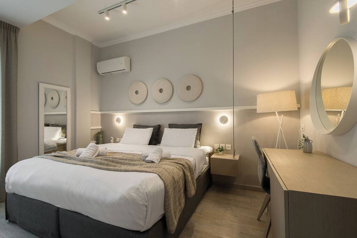 A modern hotel room with a large bed, bedside tables, a desk, and a mirror.