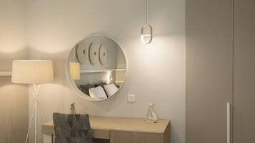 A modern bathroom with a round mirror, a bedside lamp, a vanity with a towel, and a cabinet.