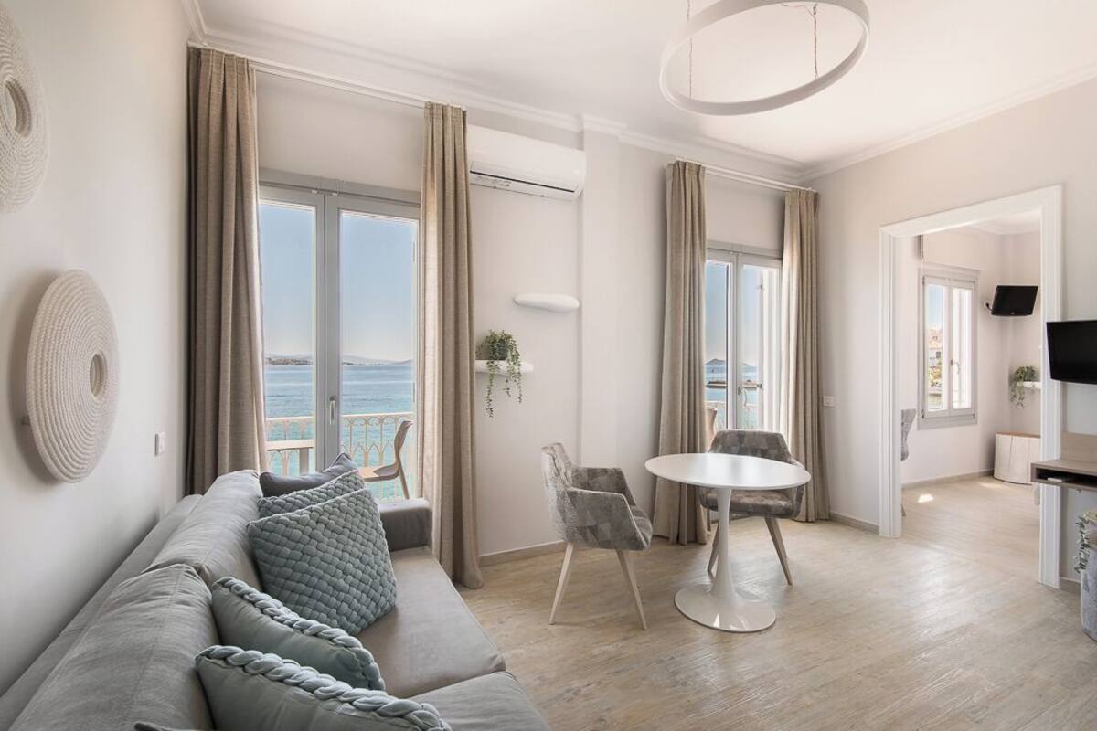 A modern living room with a sofa, a round table, and a view of the sea.