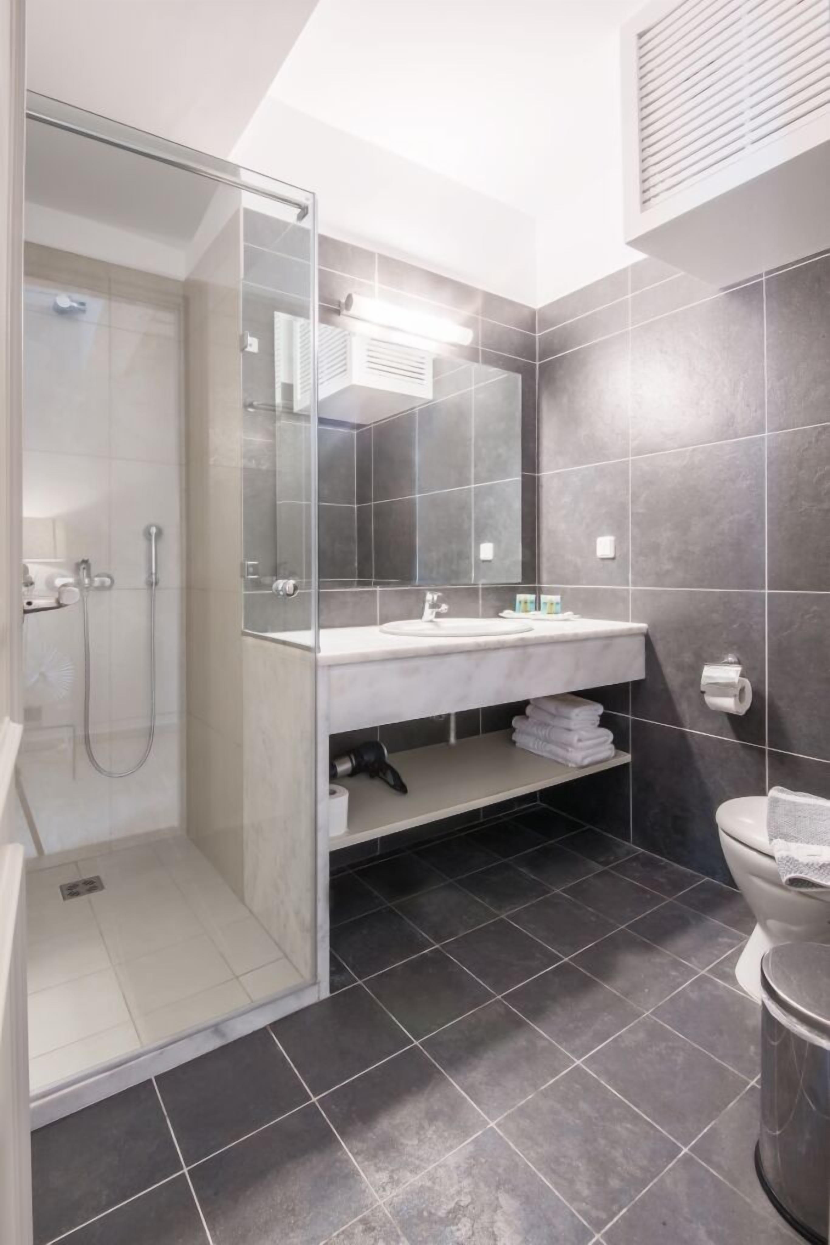 A modern bathroom with a glass-enclosed shower, a white sink, and a large mirror.