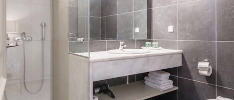 A modern bathroom with a glass-enclosed shower, a white sink, and a large mirror.