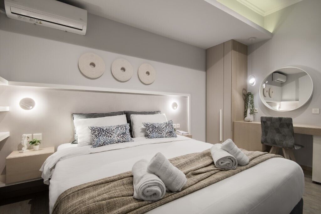 A modern bedroom with a large bed, bedside tables, a round mirror, and a ceiling light.