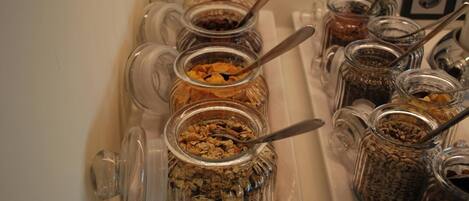 A food station with various jars containing different types of snacks and spreads, each with a spoon.
