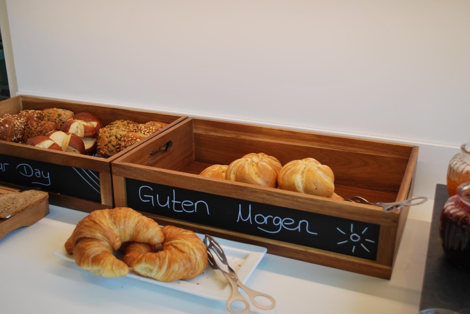 A bakery display with labeled sections for gluten-free and whole grain products, including croissants and various baked goods.