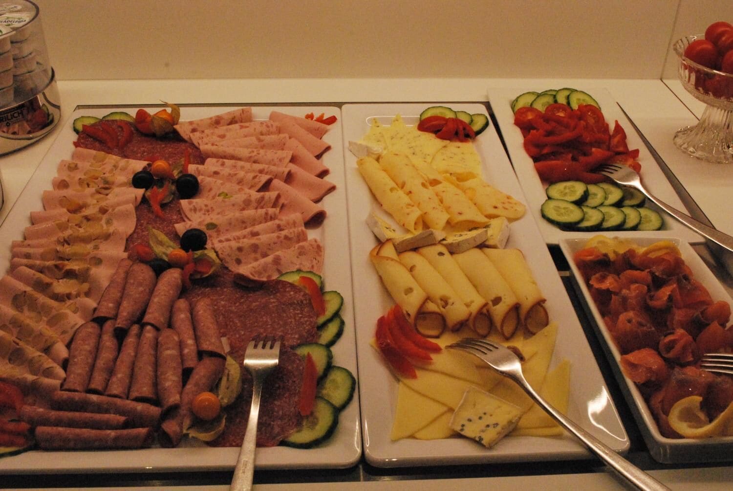 Una mesa de buffet con diferentes tipos de comida, incluyendo carnes, quesos y verduras.