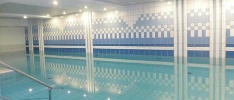 Una piscina interior con paredes de azulejos y fondo transparente.