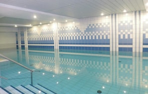 An indoor swimming pool with tiled walls and a clear pool floor.