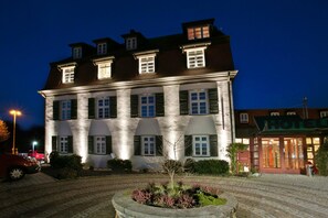 Un edificio grande de dos pisos con fachada de piedra y varias ventanas, probablemente un hotel.