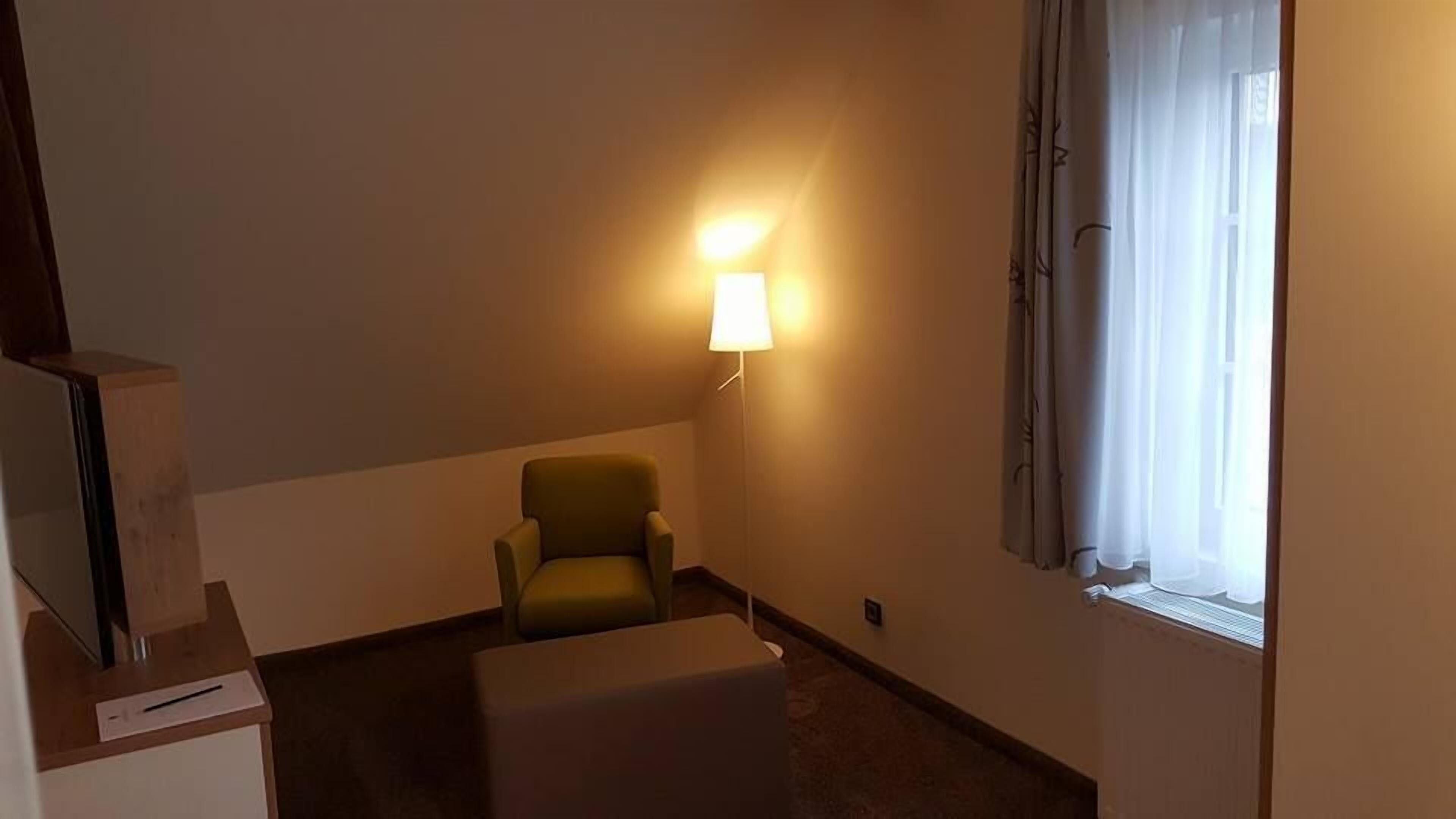 A small, dimly lit room with a single armchair and a small table.