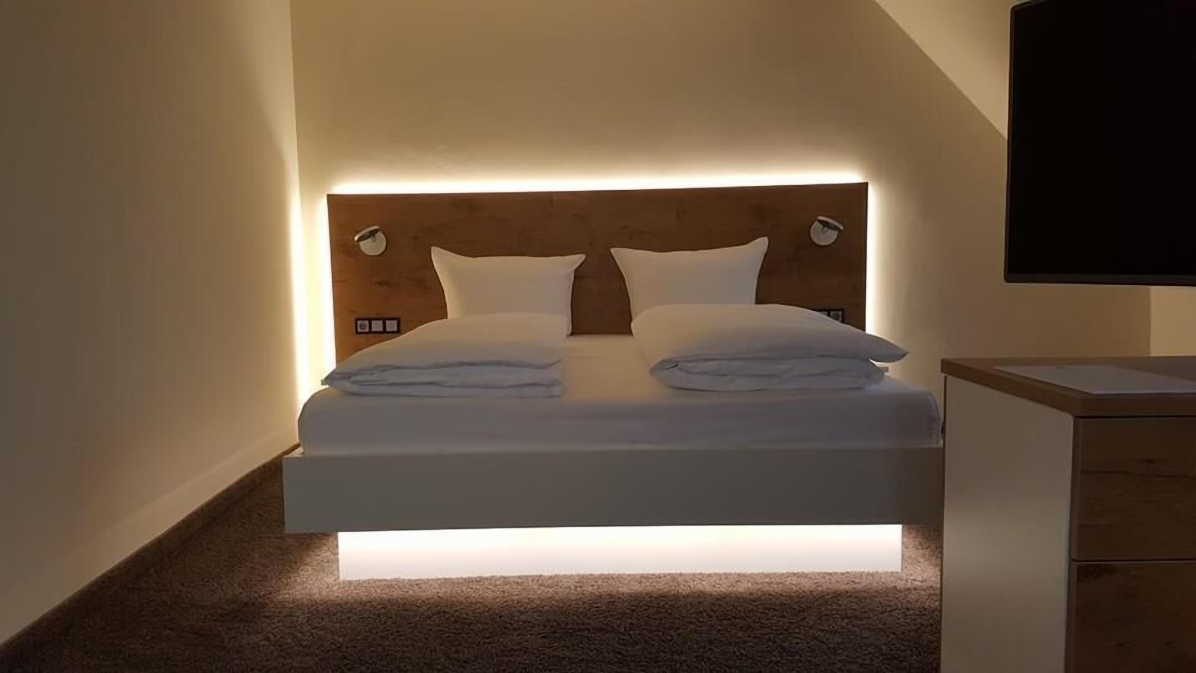 Un dormitorio moderno con cama, mesitas de noche y televisor montado.