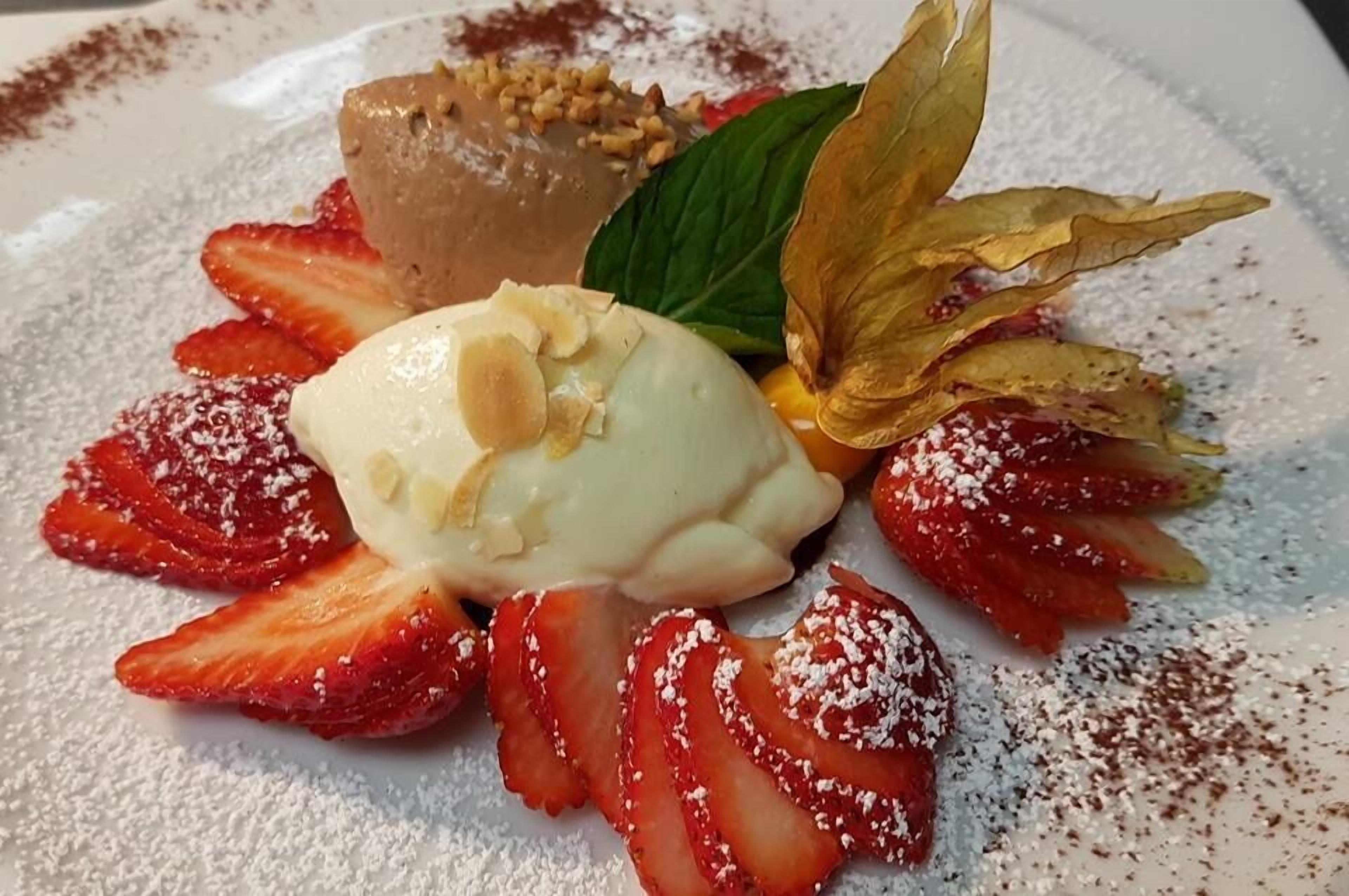 A dessert plate with strawberries, a scoop of ice cream, and a chocolate dessert.