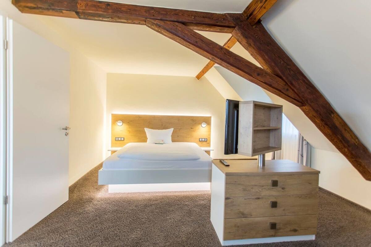 A bedroom with a bed, bedside table, and a wooden headboard.