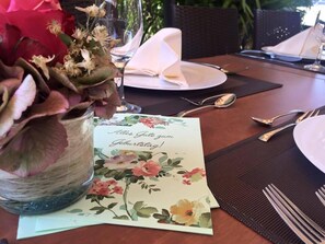 A table set with a floral napkin, a glass vase with dried flowers, and a birthday greeting card.