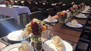 Comedor con mesas dispuestas para comer, cada una con un jarrón de flores, platos y cubiertos.