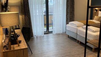 A hotel room with a wooden desk, a bed, and a view through a large window.