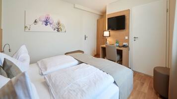 A hotel room with two beds, a desk, a TV, and a painting on the wall.
