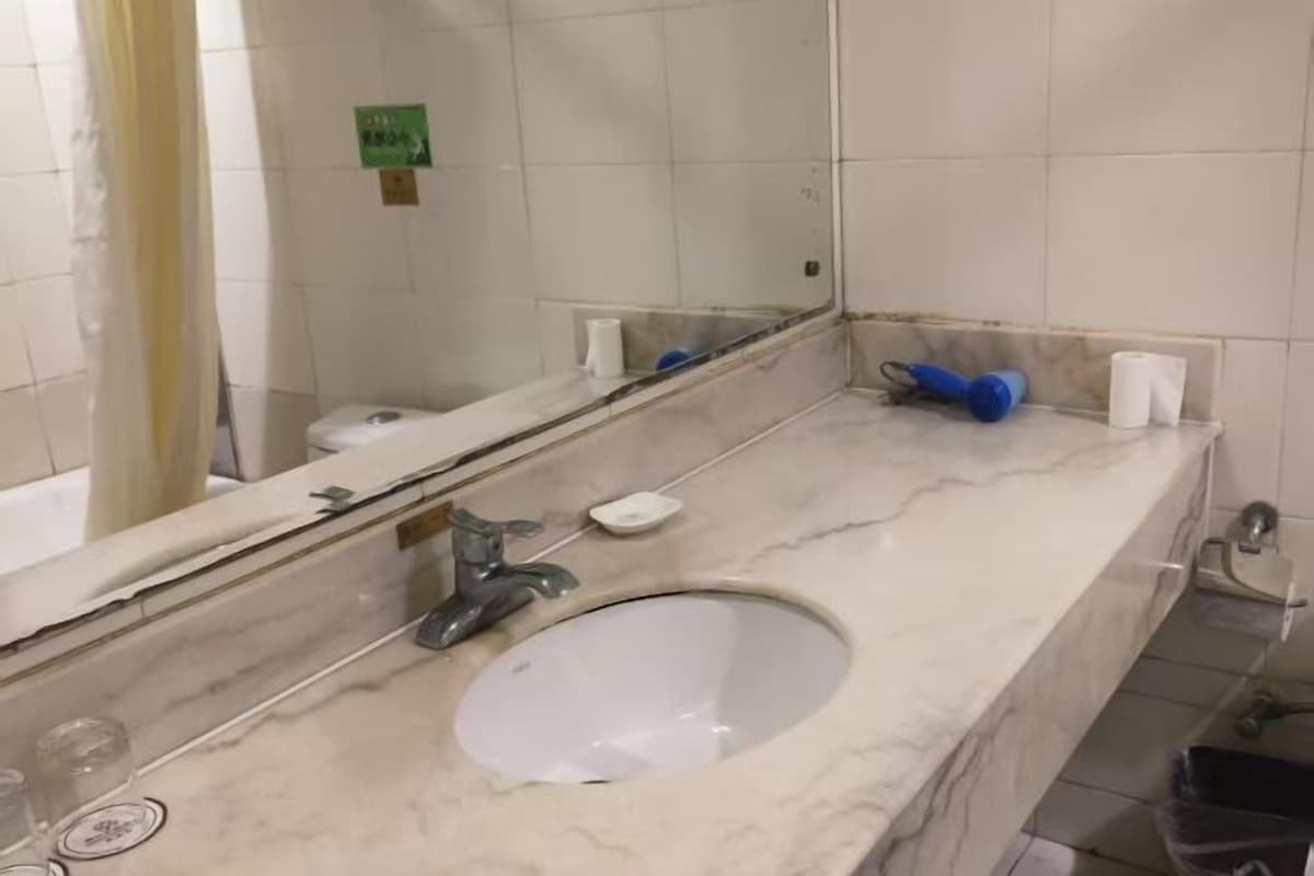 A bathroom with a white sink, mirror, and tiled walls.