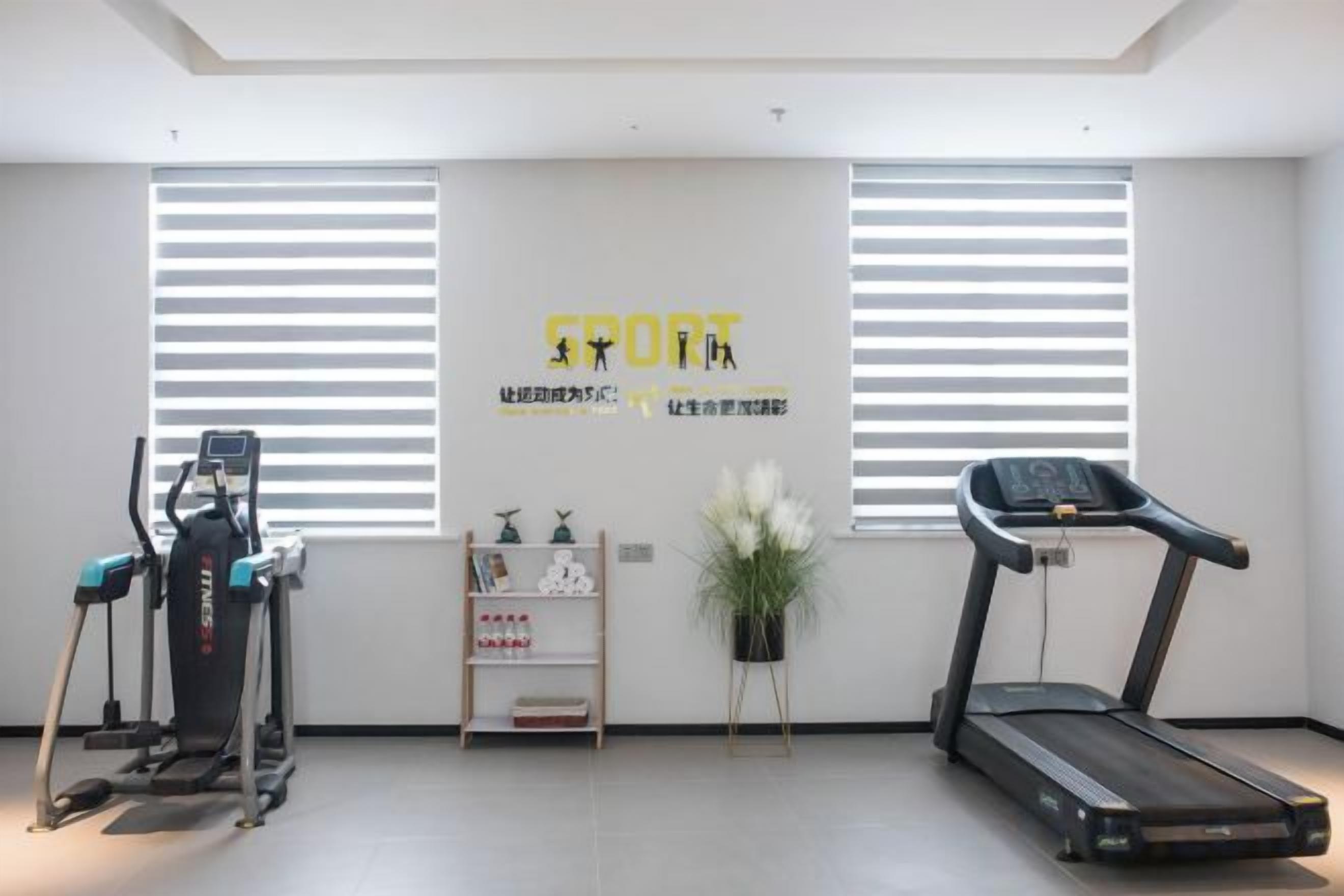 A gym with exercise equipment, a treadmill, and a wall with motivational text.