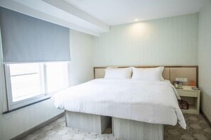 Une chambre d’hôtel avec un lit, une table de chevet et une fenêtre avec un store.