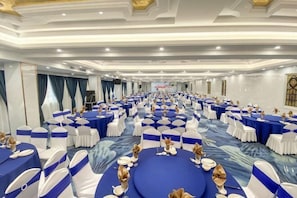 Une salle de conférence avec des tables rondes, des chaises blanches et des nappes bleues.