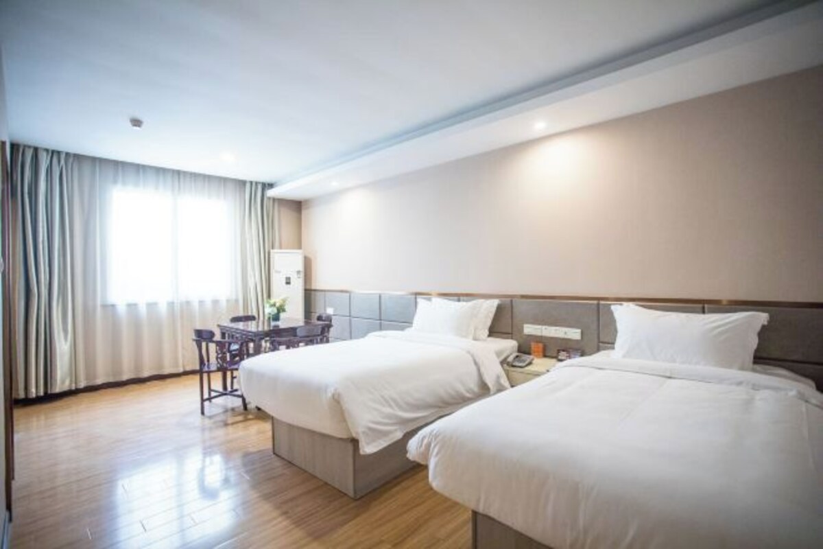 Hotellihuone, jossa on kaksi sänkyä, työpöytä ja tuoli.
