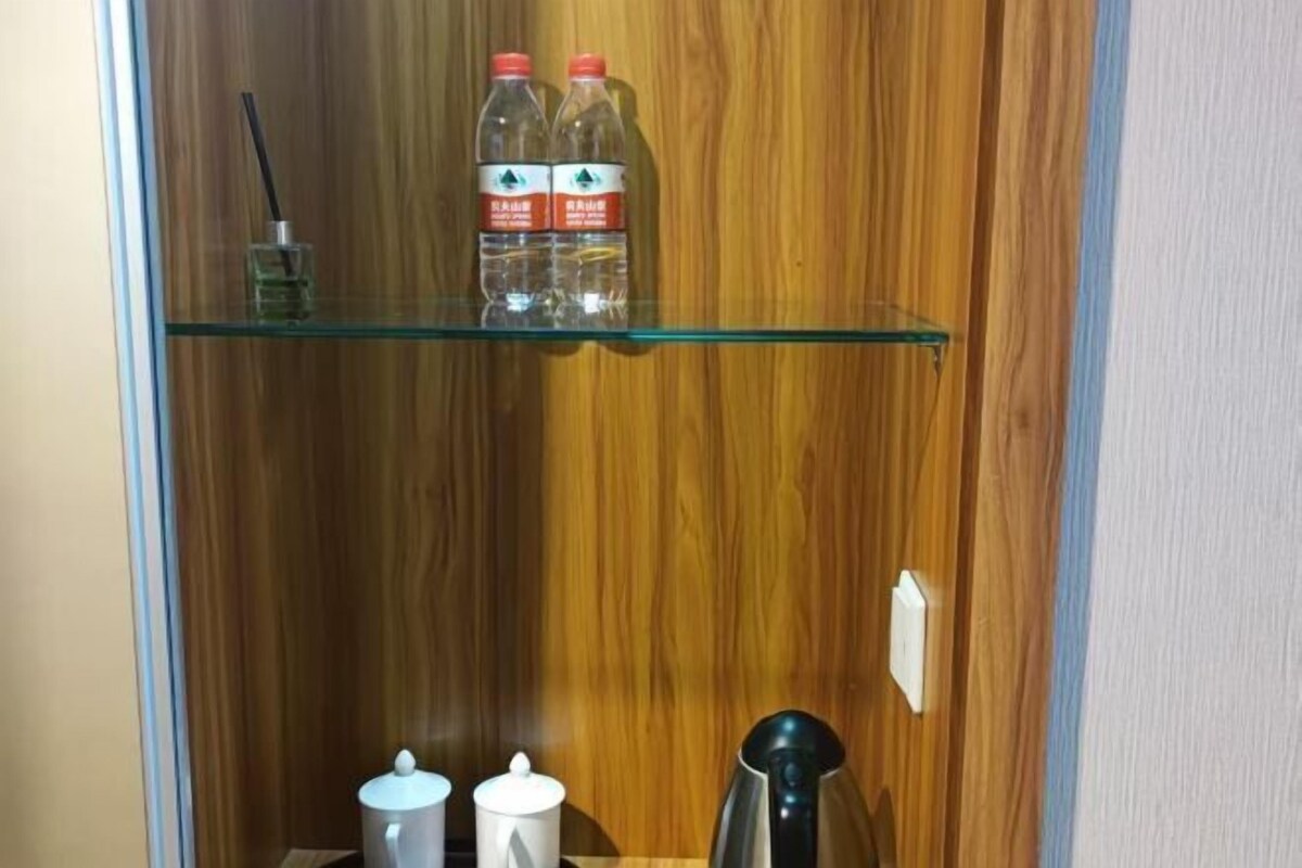A wooden interior with a glass shelf holding two bottles and a glass.