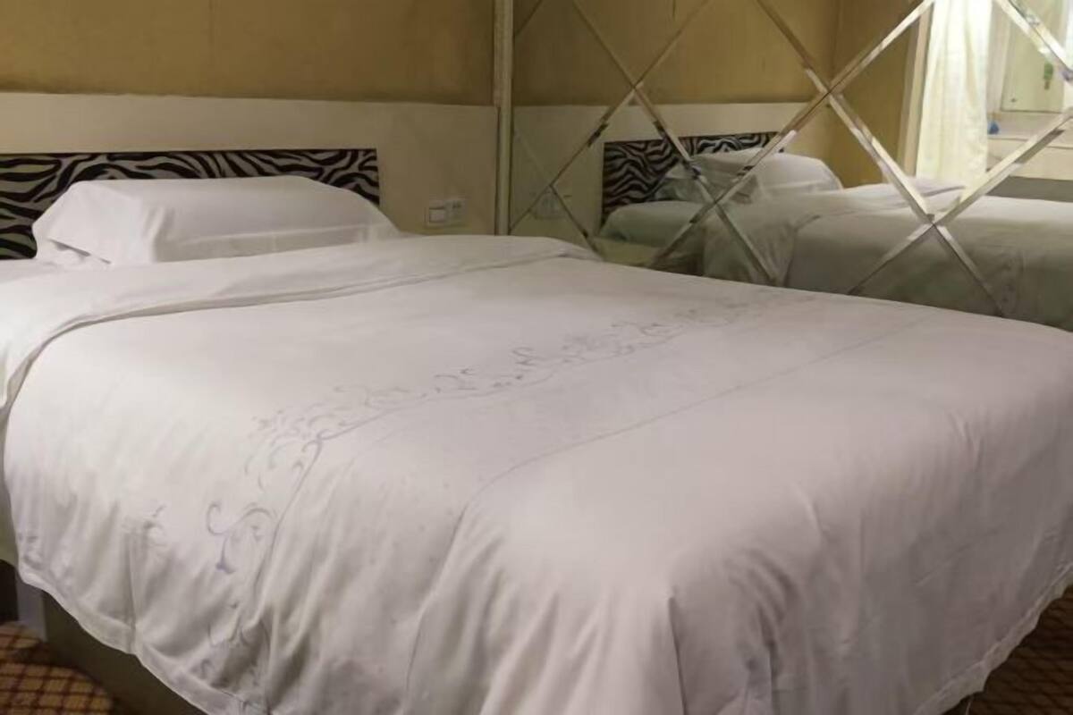 Une chambre d’hôtel avec un lit, une tête de lit à motifs zébrés et une fenêtre donnant sur un beau paysage.