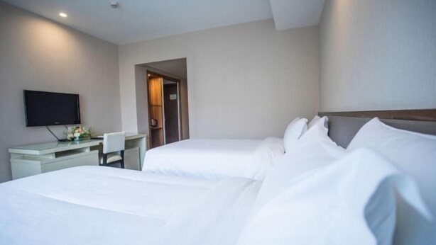 A hotel room with two beds, a desk, a chair, and a television. - Jinjiang Garden Hotel (Nantong)