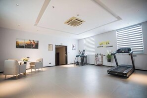 A spacious room with a treadmill, a desk, and chairs.