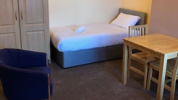 A small room with a single bed, a wooden table, a chair, and a wardrobe. - North Circular Studios 4 (Dublin)