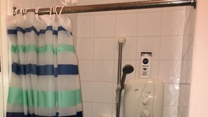 A shower area with a striped shower curtain, a handheld showerhead, and a wall-mounted control panel. - North Circular Studios 4 (Dublin)
