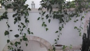 A stone staircase leading to a white-walled room with a small table and potted plants. - ArcoBello Suite Rooms (Castellana Grotte)