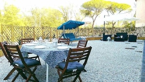 Un espace extérieur aménagé pour les repas, avec une table ronde, des chaises et un parasol bleu.