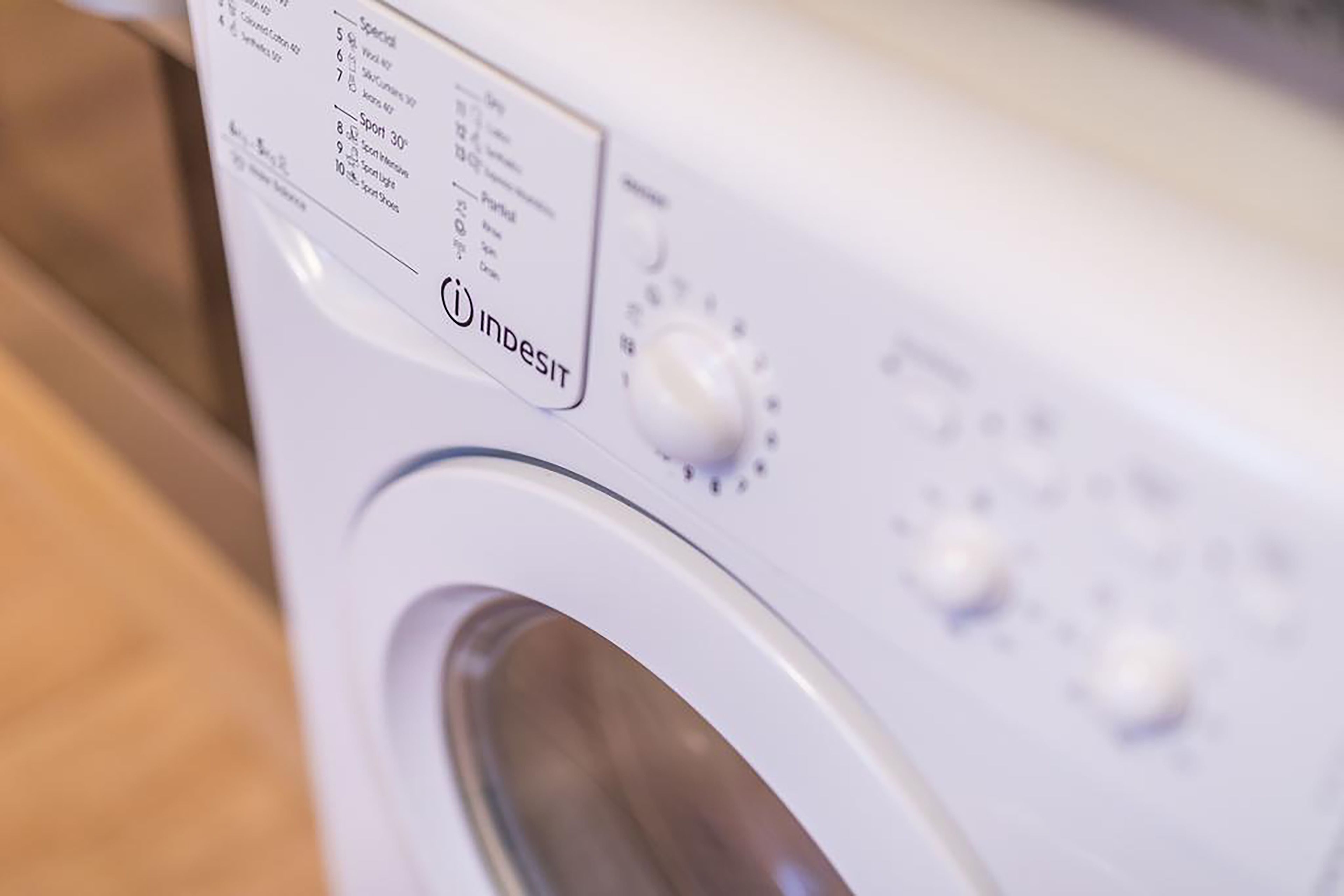 Une machine à laver blanche, dotée d’un panneau de commande et d’un bouton rotatif.