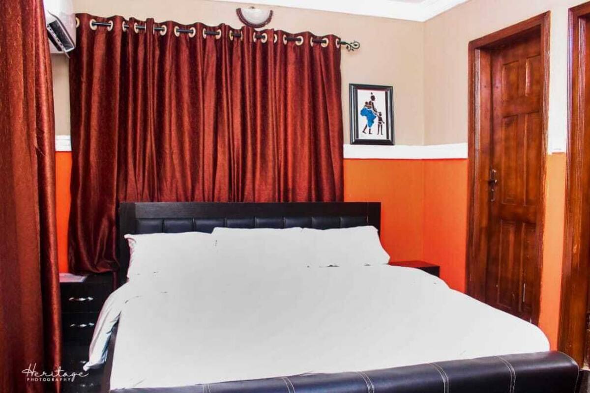 Quarto com uma cama grande, porta de madeira e quadro pendurado na parede.