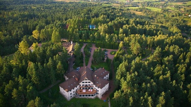 Vista aérea de un edificio grande de varios pisos rodeado de un bosque frondoso.
