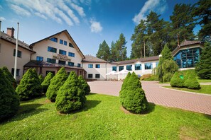 Un hôtel doté d’un grand bâtiment, d’un espace extérieur abrité et d’arbres soigneusement taillés.