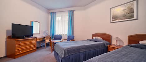 A hotel room with two beds, a desk with a television, a chair, a lamp, and a painting on the wall.