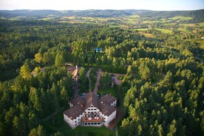 Une vue aérienne d’un grand immeuble à plusieurs étages, entouré d’une forêt dense.