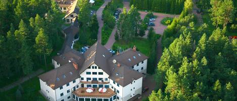 A large, multi-story building with a central courtyard surrounded by lush greenery and trees.