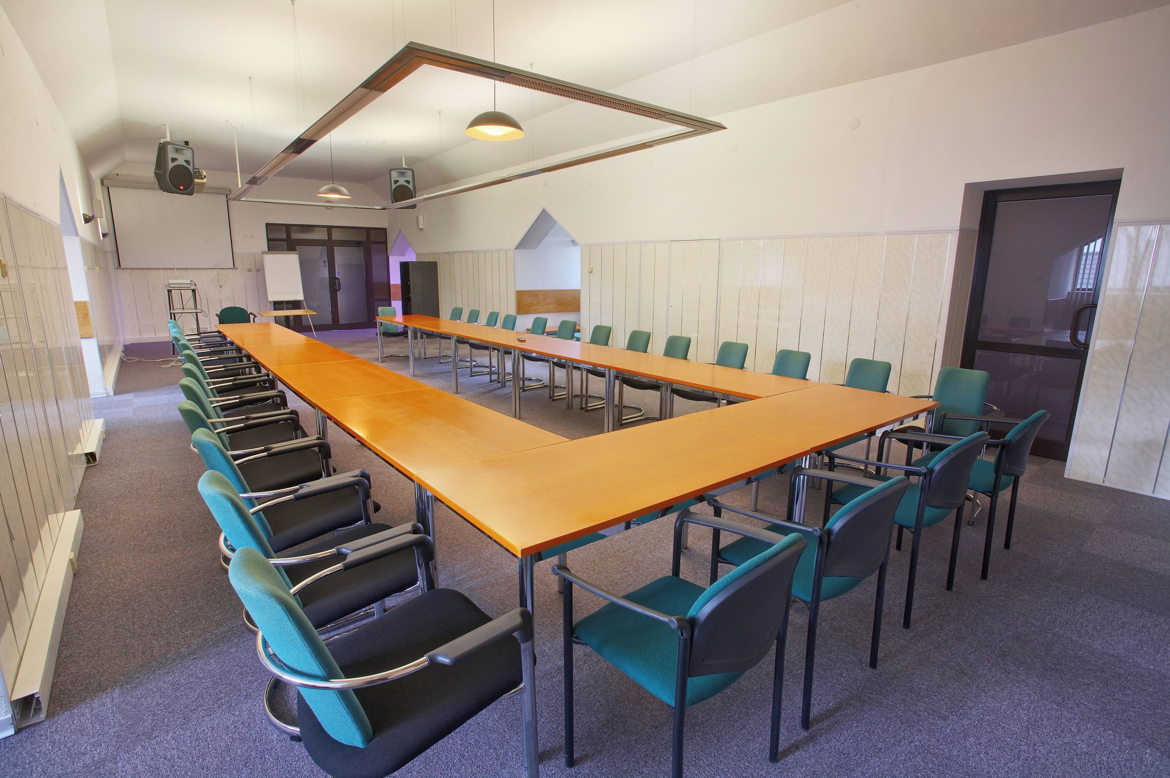 A conference room with a long table and chairs, a whiteboard, and a door.