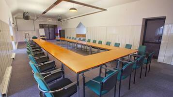 A conference room with a long table and chairs, a whiteboard, and a door.