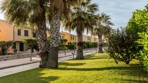 A pathway lined with palm trees and a building with a stone facade. - Residence Andrea Doria (Ragusa)