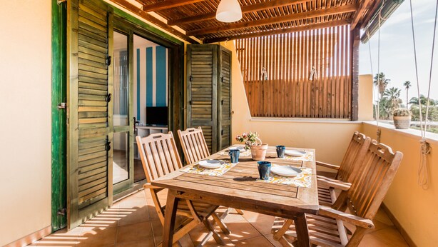 A wooden table set for two with chairs, a hanging light fixture, and a view of the outside. - Residence Andrea Doria (Ragusa)