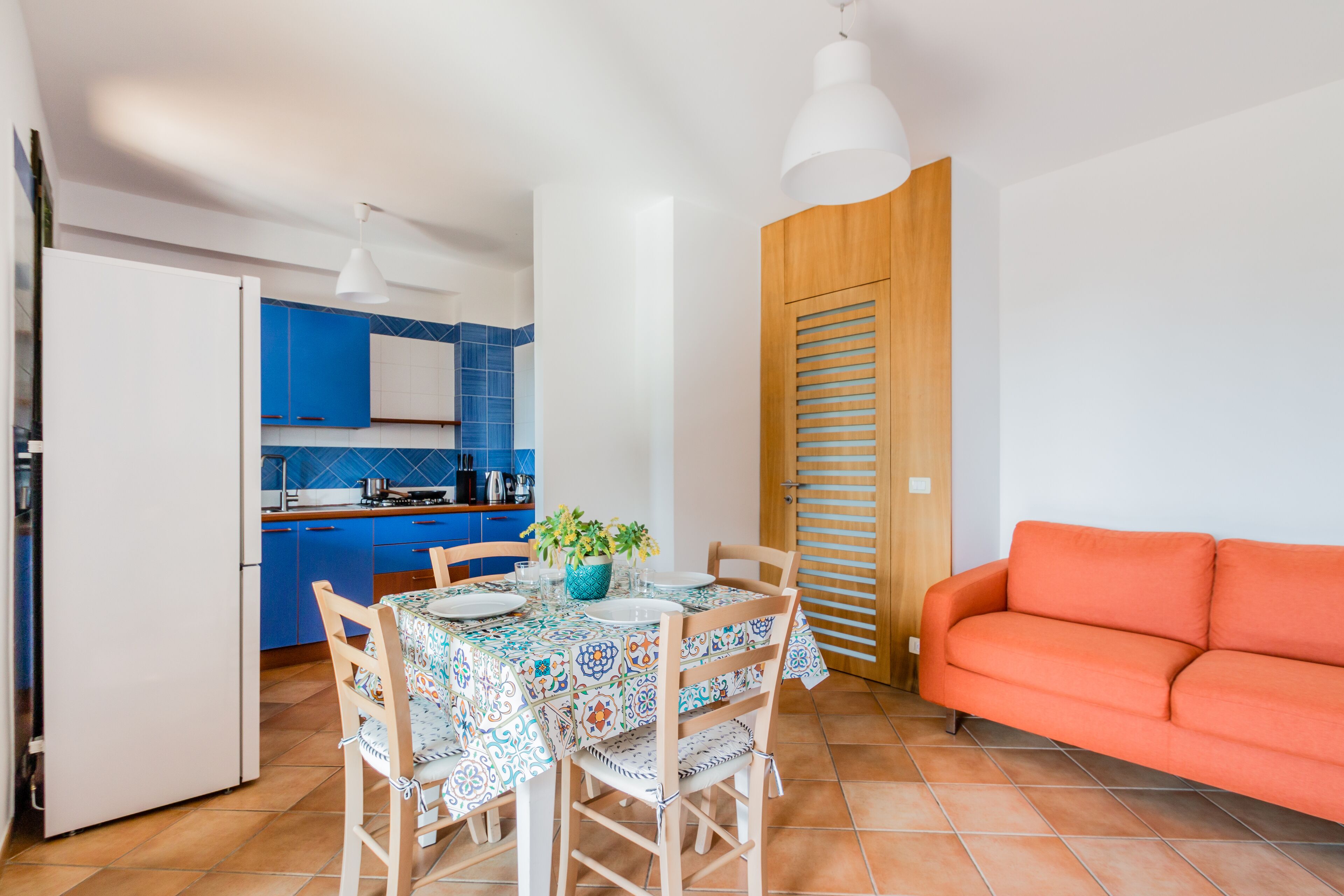 A compact living space with a kitchen area, dining table, and a sofa.