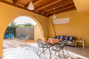 Un patio iluminado por el sol con una mesa, sillas y un sofá.